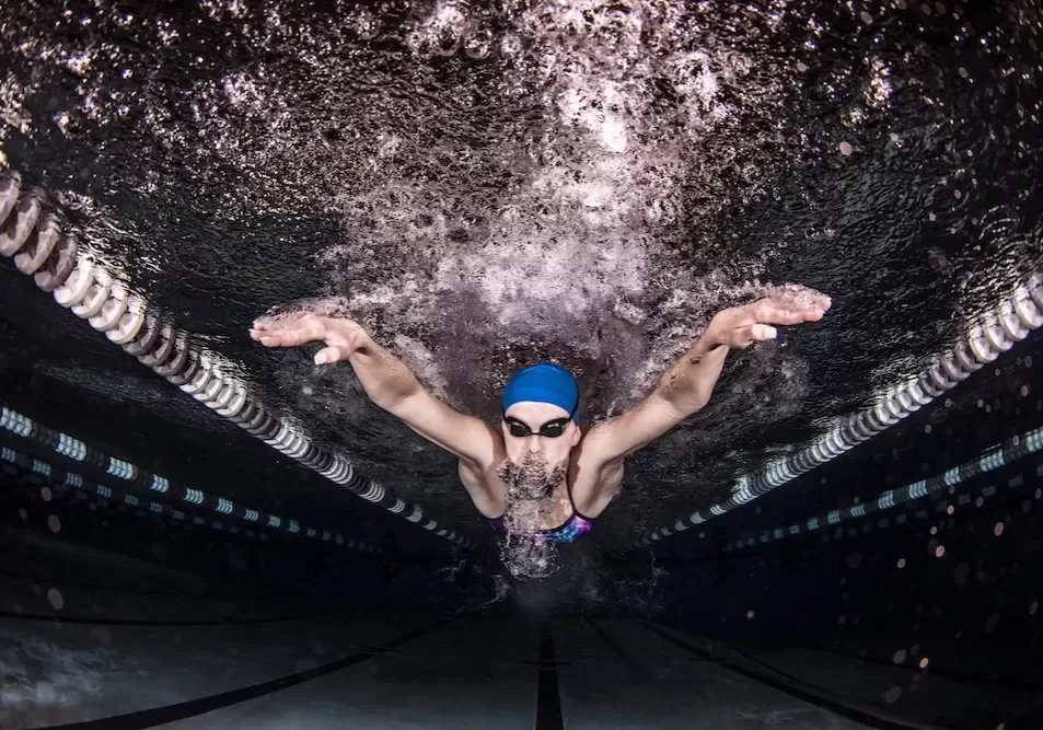 Swimmer powering through the water in a pool at night